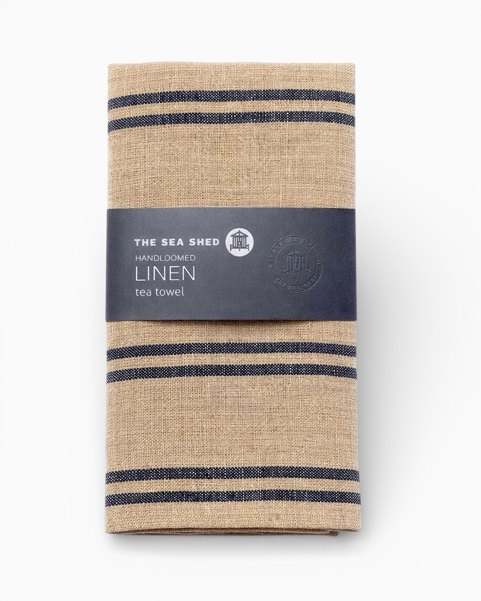 Folded linen tea towel with blue stripes and 'The Sea Shed' label on a white background. Striped linen tea towel
100% linen tea towel
Hand-loomed linen tea towel
Natural linen kitchen towel
Coastal linen tea towel
